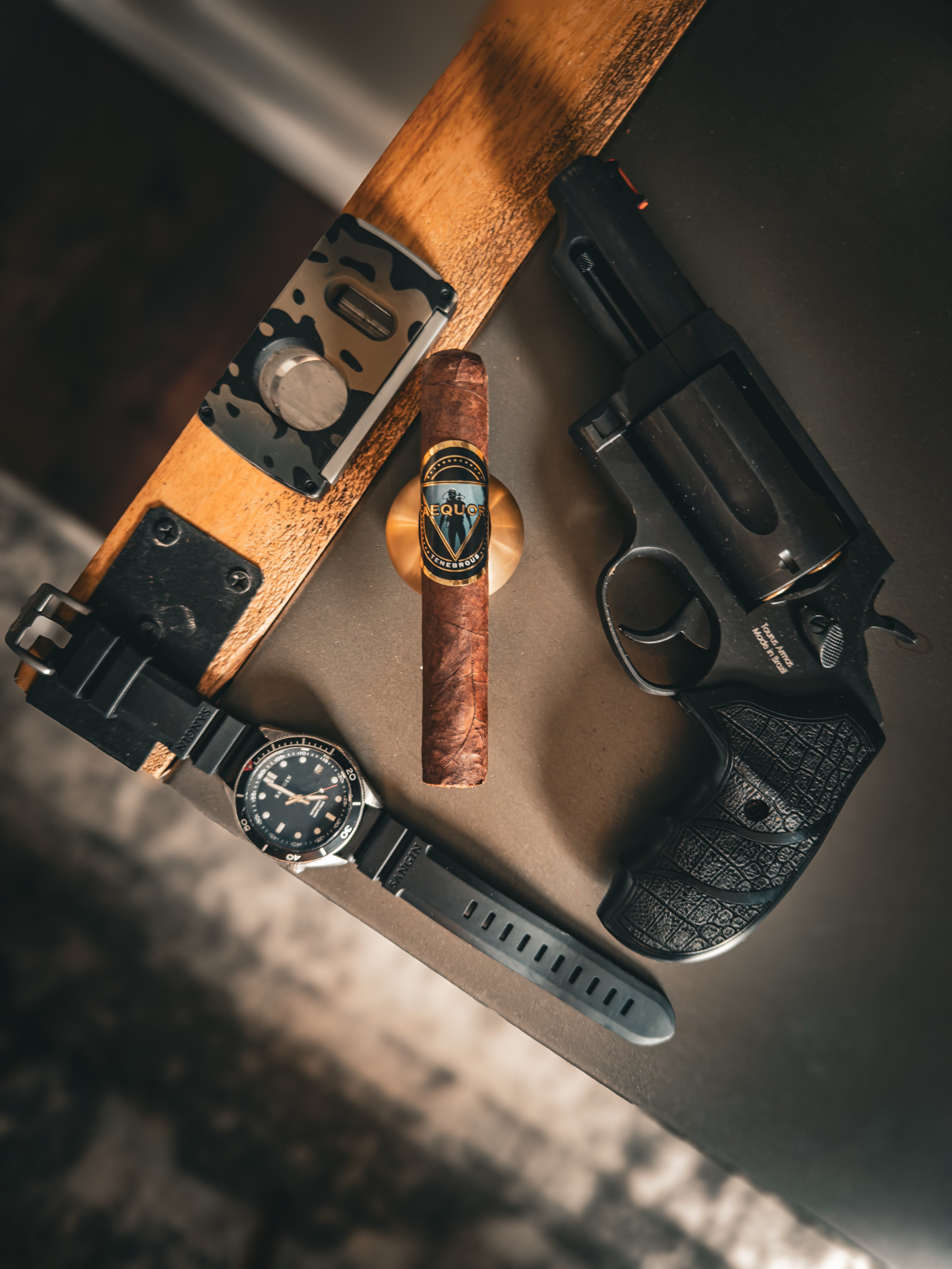 Revolver, watch, Sangin Neptune and a Tenebrous Aequor on a whiskey table.